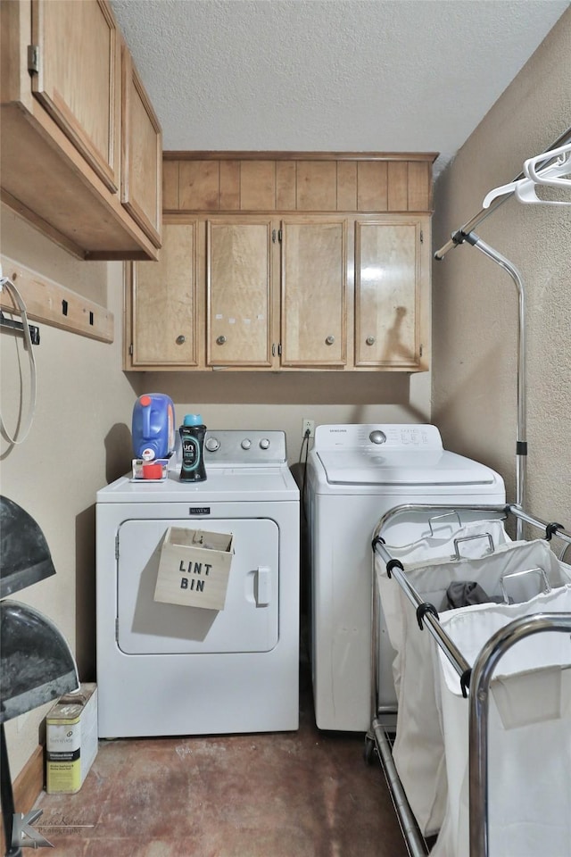 washroom featuring cabinets, a textured ceiling, and washer and clothes dryer