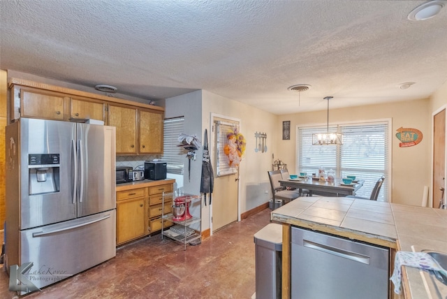 kitchen featuring an inviting chandelier, decorative light fixtures, tile countertops, stainless steel appliances, and decorative backsplash