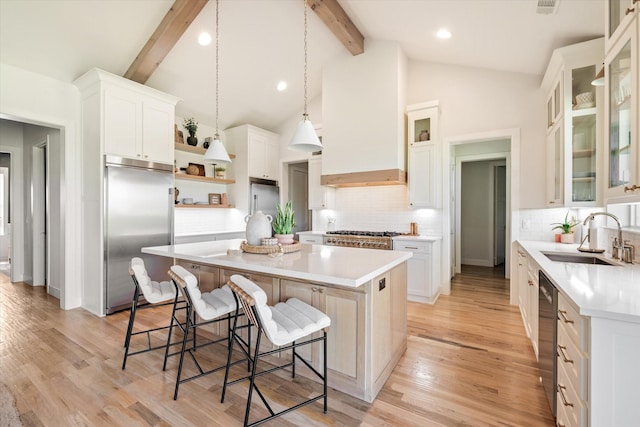 kitchen featuring light countertops, appliances with stainless steel finishes, white cabinets, a kitchen island, and a sink