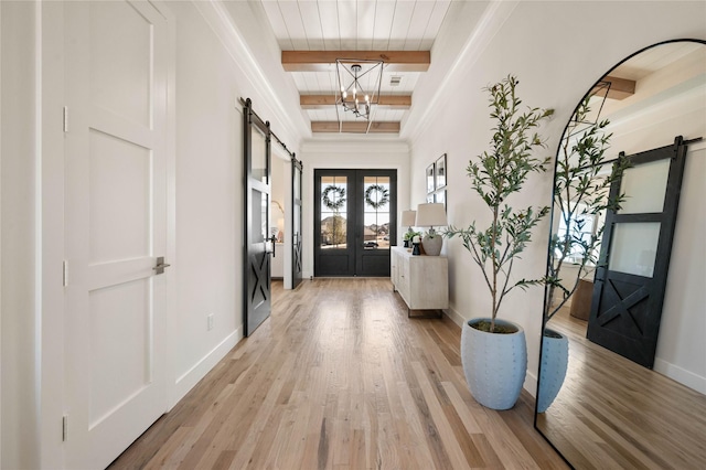 entryway featuring a barn door, baseboards, light wood-style floors, french doors, and beamed ceiling