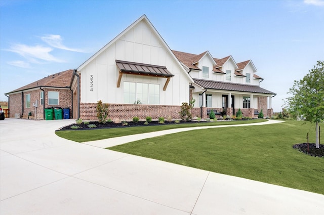 view of front facade featuring a porch, brick siding, board and batten siding, a standing seam roof, and a front yard