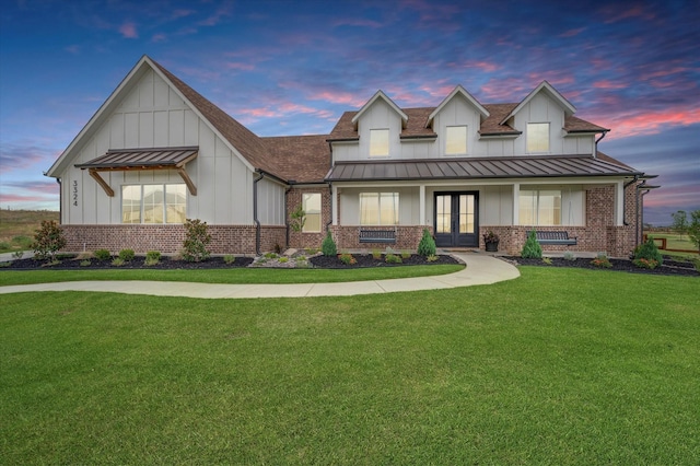 modern farmhouse style home featuring board and batten siding, a standing seam roof, brick siding, and french doors