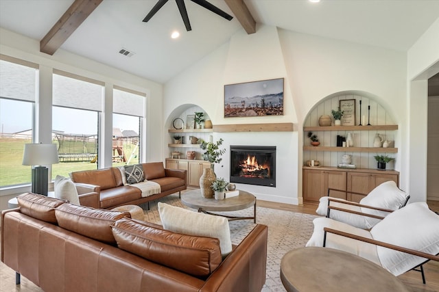 living area featuring a large fireplace, plenty of natural light, light wood-style flooring, and beamed ceiling