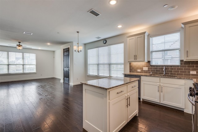 kitchen featuring stone counters, appliances with stainless steel finishes, sink, hanging light fixtures, and a center island