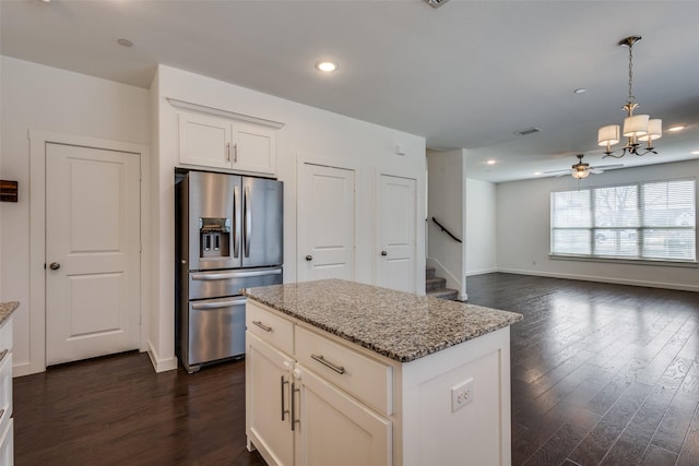 kitchen featuring stainless steel refrigerator with ice dispenser, light stone countertops, a center island, and white cabinets