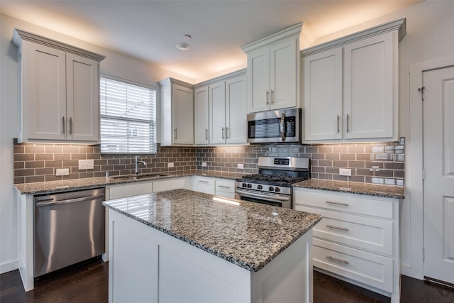 kitchen featuring sink, stainless steel appliances, a center island, tasteful backsplash, and white cabinets