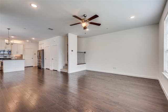 unfurnished living room with dark wood-type flooring and ceiling fan with notable chandelier