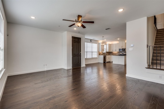 unfurnished living room with dark hardwood / wood-style floors and ceiling fan with notable chandelier