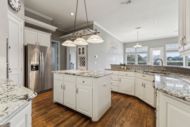 kitchen featuring a kitchen island, light stone counters, white cabinets, and stainless steel refrigerator with ice dispenser