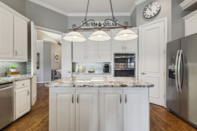 kitchen featuring appliances with stainless steel finishes, white cabinets, pendant lighting, and a center island