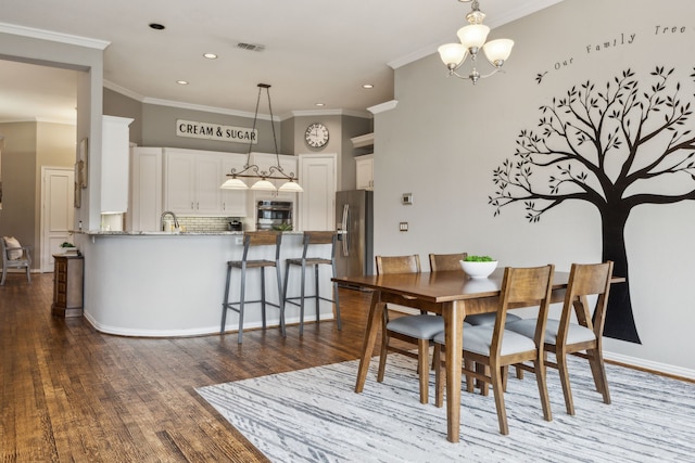 dining space featuring hardwood / wood-style flooring, crown molding, and a chandelier