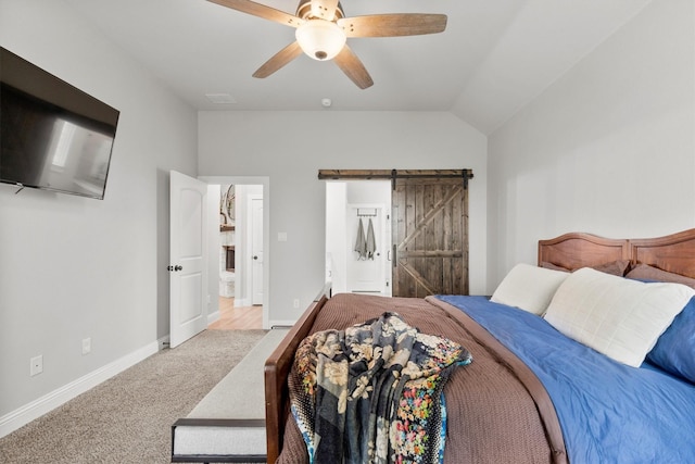 bedroom featuring vaulted ceiling, light colored carpet, ceiling fan, a barn door, and ensuite bath