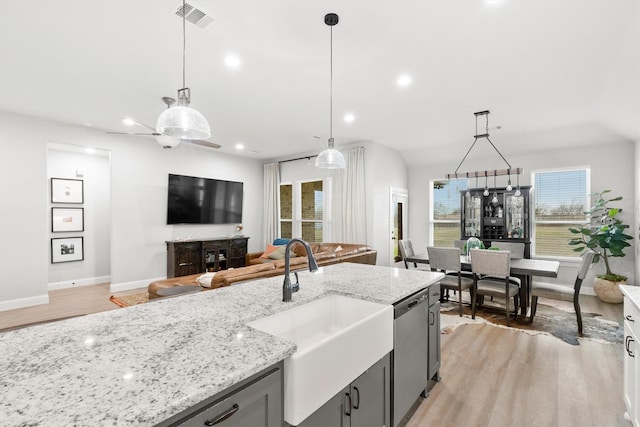 kitchen with sink, stainless steel dishwasher, light stone counters, and decorative light fixtures