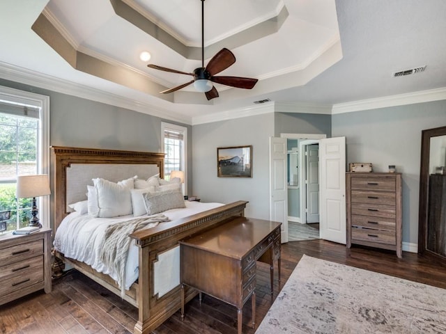 bedroom with dark wood-type flooring, ceiling fan, ornamental molding, and a raised ceiling