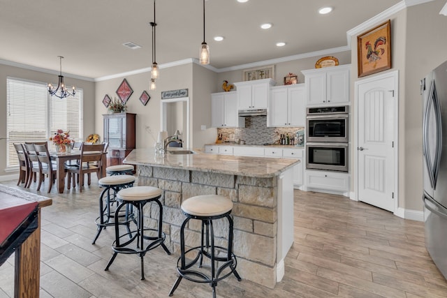 7728 County Road 1205, Rio Vista, TX 76093 - kitchen with appliances with stainless steel finishes, under cabinet range hood, crown molding, decorative backsplash, and a kitchen breakfast bar