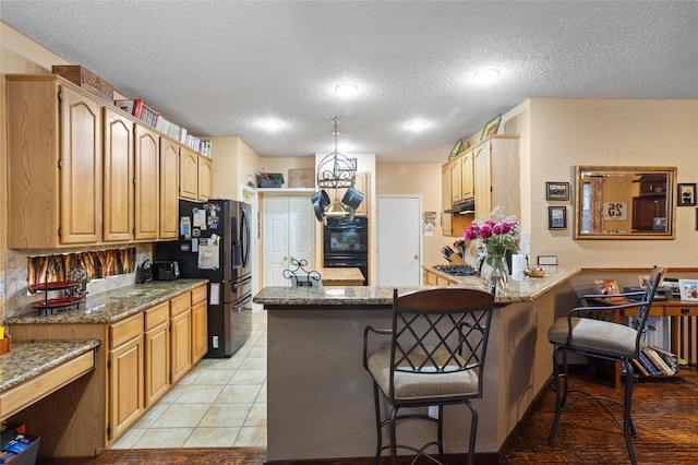 kitchen featuring a breakfast bar area, stainless steel fridge with ice dispenser, light tile patterned floors, kitchen peninsula, and light stone countertops