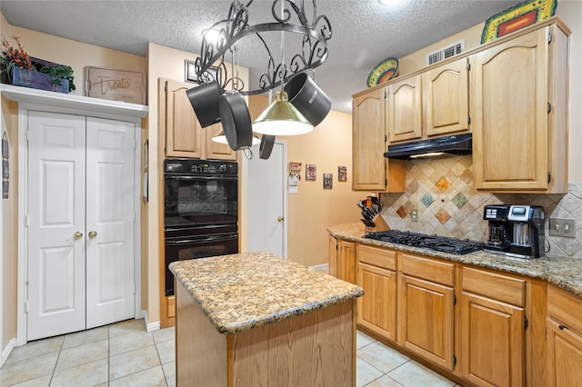 kitchen with a kitchen island, light stone countertops, black appliances, a textured ceiling, and light tile patterned flooring