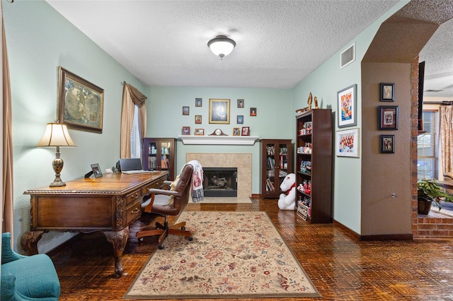 office space featuring dark wood-type flooring, a fireplace, and a textured ceiling