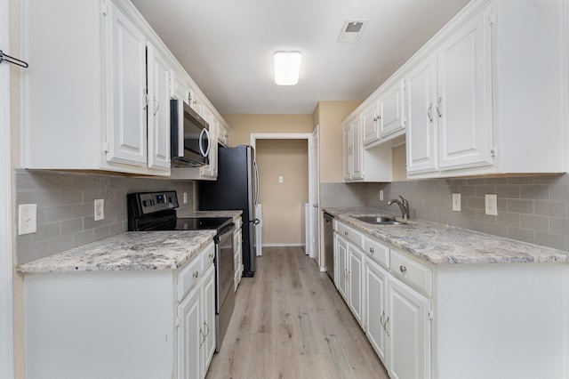 kitchen with stainless steel appliances, light hardwood / wood-style floors, sink, and white cabinets