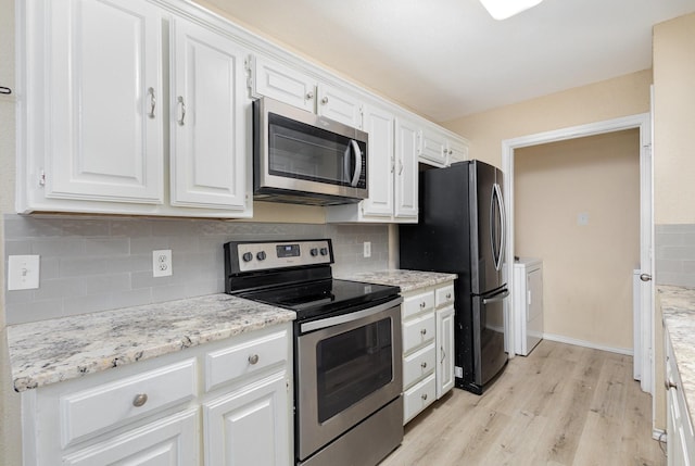 kitchen with washing machine and dryer, light hardwood / wood-style floors, white cabinets, and appliances with stainless steel finishes