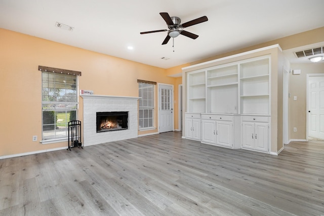 unfurnished living room with a brick fireplace, ceiling fan, and light hardwood / wood-style flooring