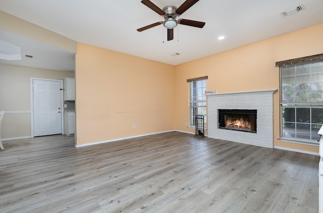 unfurnished living room with a fireplace, light hardwood / wood-style flooring, and ceiling fan