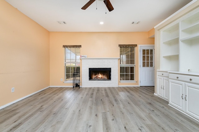 unfurnished living room featuring a fireplace, light hardwood / wood-style floors, and ceiling fan