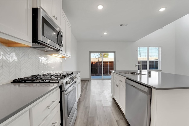 1004 Emil Pl, Allen, TX 75013 - kitchen featuring appliances with stainless steel finishes, backsplash, an island with sink, light wood-style flooring, and recessed lighting