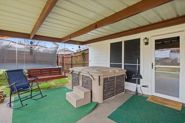 view of patio / terrace with a trampoline, fence, and a hot tub