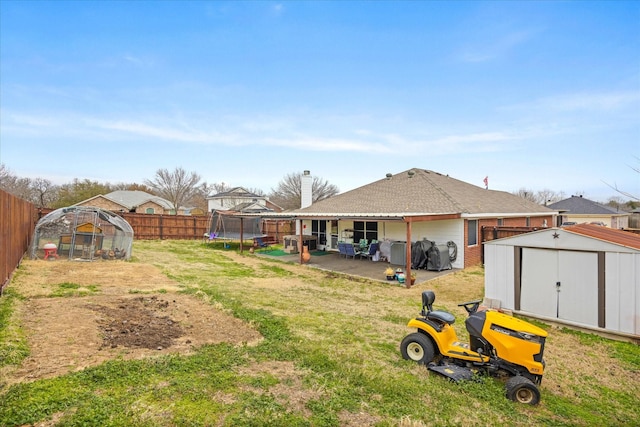 view of yard with an outbuilding, a storage shed, a trampoline, and a fenced backyard