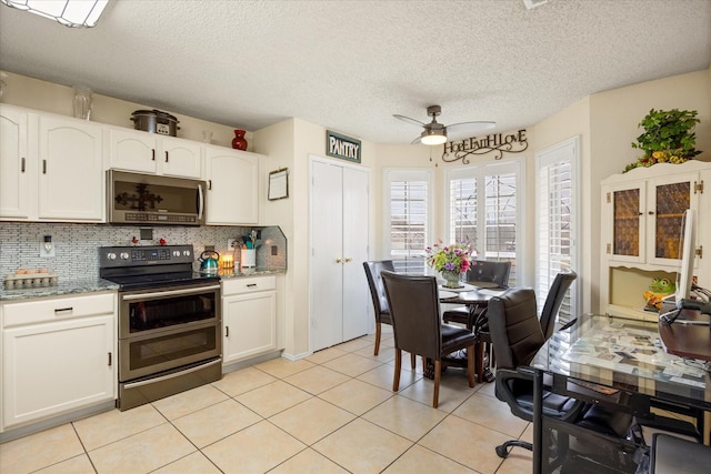 kitchen with light tile patterned floors, white cabinets, decorative backsplash, appliances with stainless steel finishes, and light stone countertops