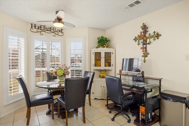 dining space featuring light tile patterned floors, ceiling fan, a textured ceiling, and visible vents