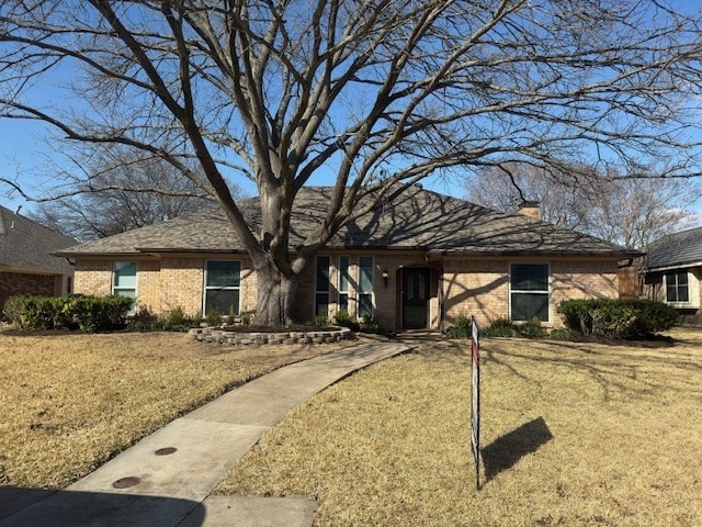 view of front of home with a front yard, brick siding, and a chimney