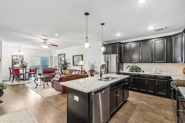 kitchen with dark hardwood / wood-style floors, pendant lighting, an island with sink, sink, and stainless steel appliances