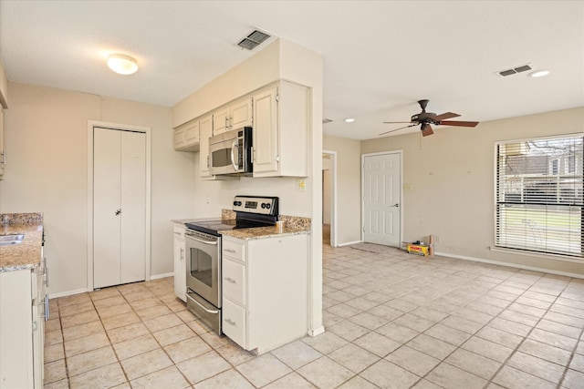 kitchen featuring appliances with stainless steel finishes, visible vents, light stone counters, and baseboards