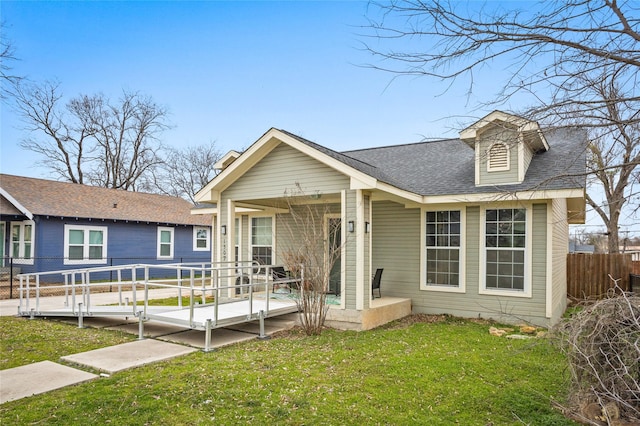 view of front of home featuring a shingled roof, a porch, fence, and a front lawn