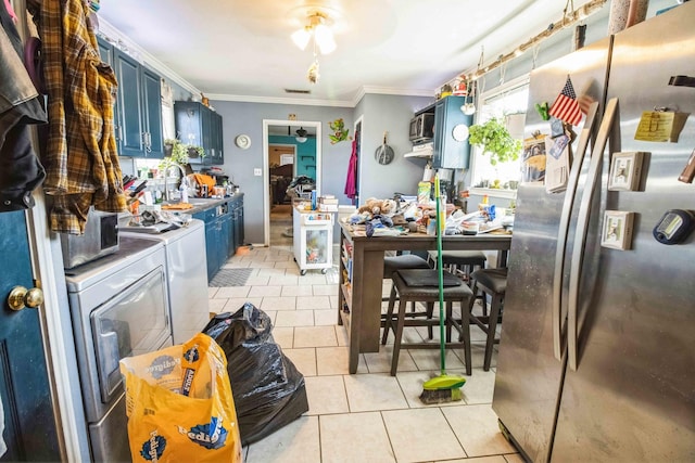 kitchen with light tile patterned floors, blue cabinets, stainless steel fridge, and independent washer and dryer