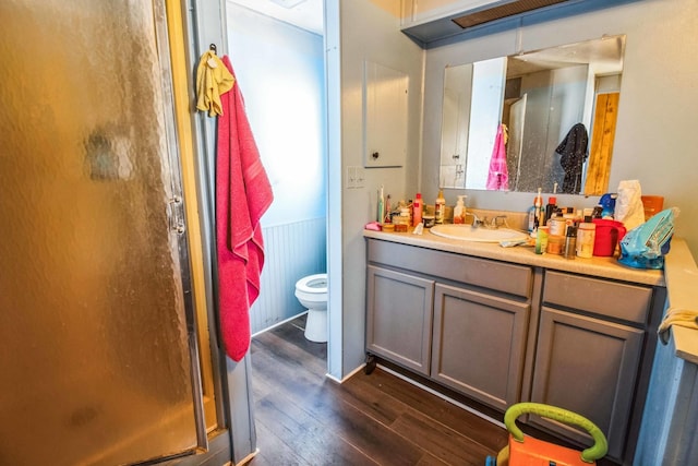 bathroom featuring toilet, vanity, hardwood / wood-style floors, and a shower with shower door