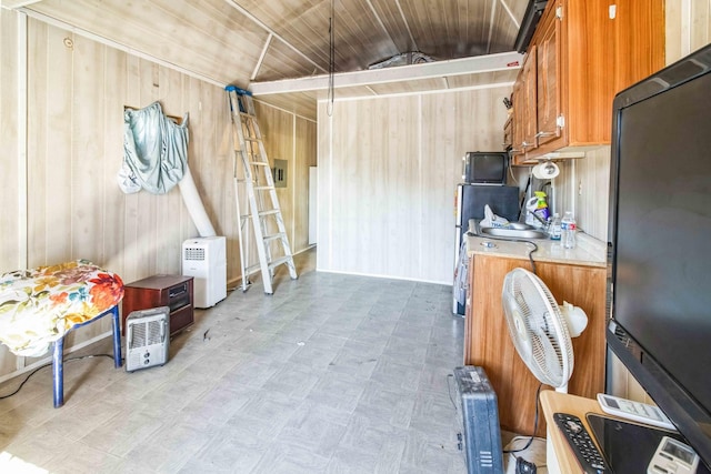 kitchen with wooden ceiling, black refrigerator, vaulted ceiling, and wooden walls