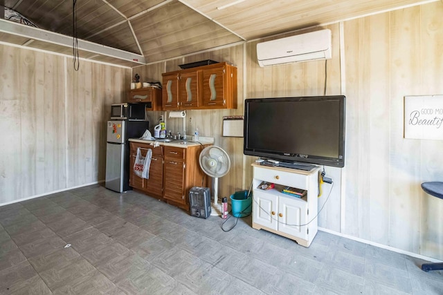 kitchen featuring lofted ceiling, a wall mounted air conditioner, stainless steel refrigerator, wooden ceiling, and wooden walls