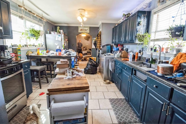 kitchen featuring blue cabinetry, appliances with stainless steel finishes, washer and dryer, and a wealth of natural light