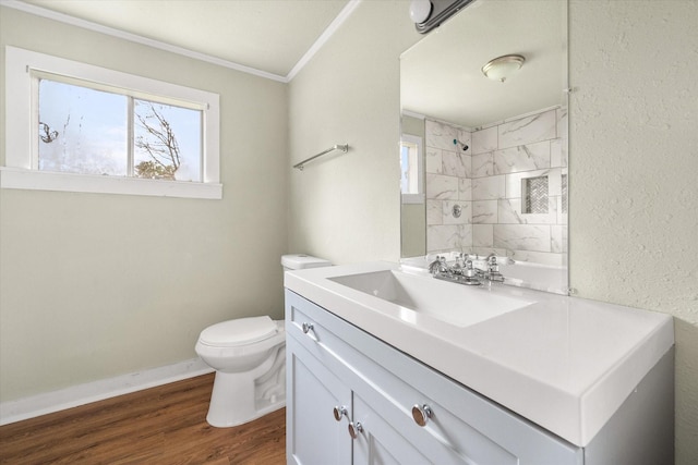 bathroom featuring tiled shower, vanity, wood-type flooring, ornamental molding, and toilet