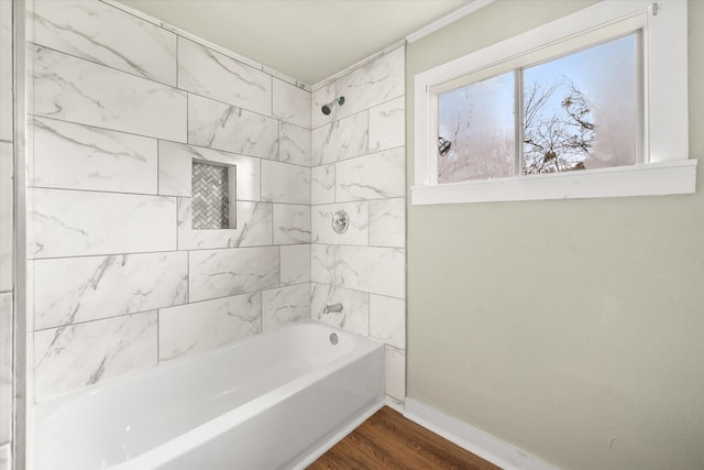 bathroom with hardwood / wood-style flooring and tiled shower / bath