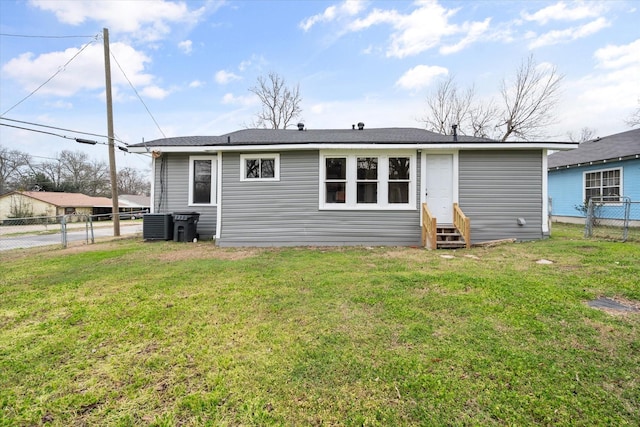 rear view of property with a lawn and central air condition unit