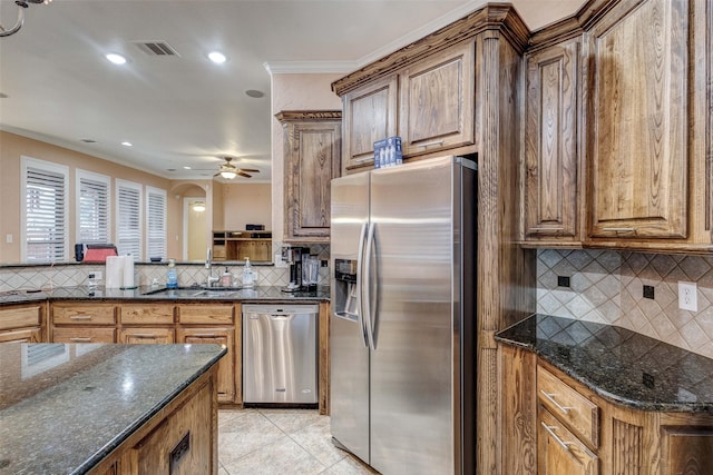 kitchen featuring light tile patterned flooring, appliances with stainless steel finishes, sink, dark stone countertops, and decorative backsplash