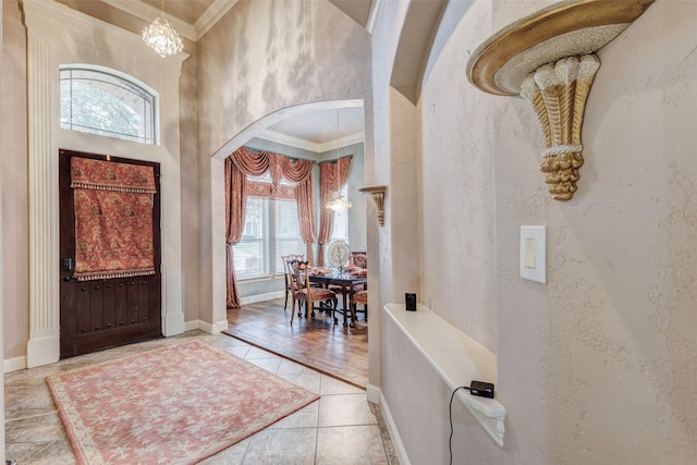 tiled foyer entrance with a towering ceiling, ornamental molding, and a chandelier