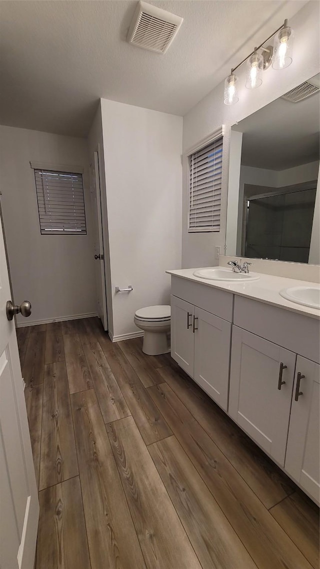 bathroom with hardwood / wood-style floors, vanity, a textured ceiling, toilet, and walk in shower