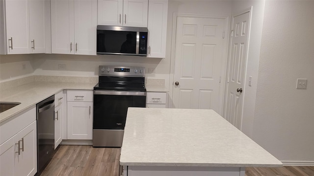 kitchen featuring white cabinetry, stainless steel appliances, a center island, and light hardwood / wood-style floors