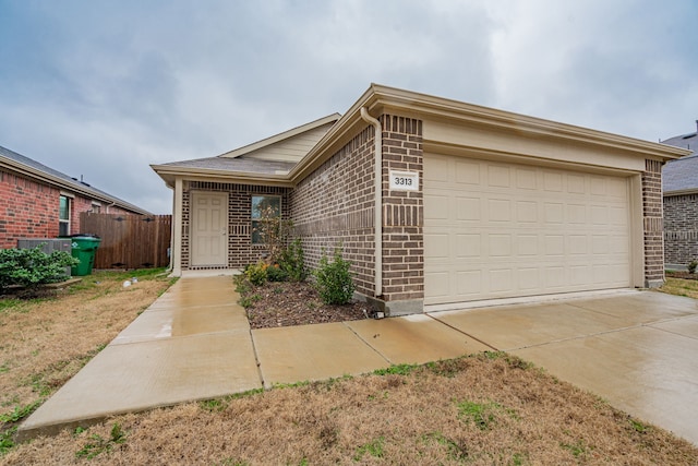 single story home featuring a garage, driveway, fence, and brick siding