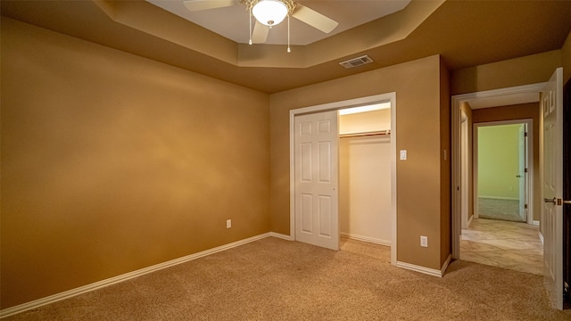 unfurnished bedroom with ceiling fan, light colored carpet, and a raised ceiling